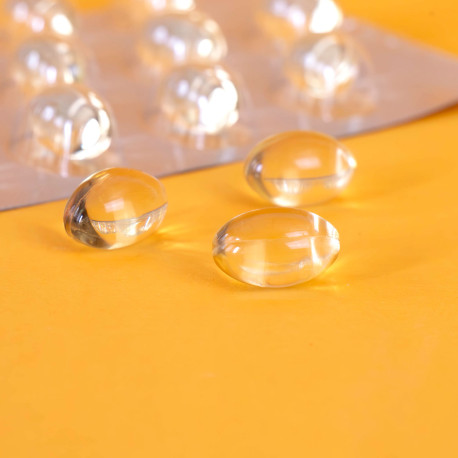Capsules d’oméga 3 ambrées et translucides posées près de leur plaquette blister
